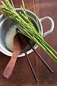 Reis und Ähren, Kochlöffel und Essstäbchen im Reiskochtopf