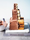 A cake in the shape of a knight's castle being spread with chocolate buttercream