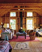 Teilweise sichtbares Bett und Wohnbereich mit modernem Sofa und Vintage Ledersessel in rustikaler Holzhütte in Maine