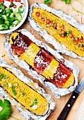 Corn cobs with Parma ham, parmesan, spring onions and sliced chillies, in aluminium foil
