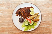 Spare ribs with potato wedges, barbecue sauce and a side salad
