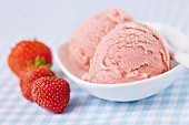 A few fresh strawberries alongside two scoops of home-made strawberry ice cream