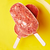 Two home-made ice lollies with cherry ice cream, on a plate