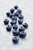 Fresh blueberries lying on a patterned tablecloth (close-up)
