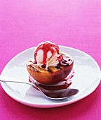 A grilled peach half with vanilla ice cream and fruit sauce