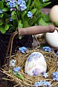 Easter egg decorated with forget-me-nots in small basket