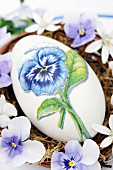 Goose egg decorated with pansy using napkin decoupage
