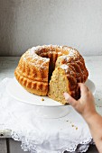 A child's hand reaching for a slice of Bundt cake