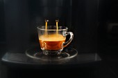 Coffee flowing from an espresso machine into a glass cup