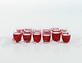 Lots of schnapps glasses on crushed ice with cherry liqueur and cherries