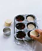 Mini summer puddings being made in a muffin tin