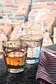 Weinglas und Wasserglas auf Steinmauer über der Stadt Nizza