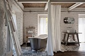 Freistehende Vintage Badewanne hinter mit Vorhang abtrennbarem Bereich, geweisselte Ziegelwände und Fliesenboden mit grauweissem Muster