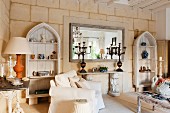 Limestone wall with shabby-chic wooden shelves, console table and mirror in restored, French country house