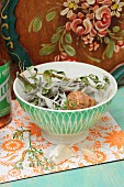 Dried herbs and Champagne cork in old, French drinking bowl on 70's board in kitchen; rustic tray with country-style painting in background