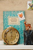 Vintage ornaments on bookshelf; animal-motif postage stamps, decorative book cover, toy deer, X and 8 printing blocks and 60s Junghans alarm clock