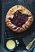 Raspberry galette (a rustic tart) on a cooling rack, and a pot of custard