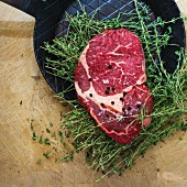 Rib eye steak with thyme on a black frying pan