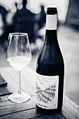 Weissweinglas und Weinflasche auf Holztisch im Restaurant