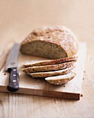 A partly sliced loaf of bread on a chopping board