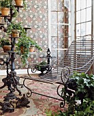 Wrought iron lounger and conservatory furnishings with trailing ivy combined with floral wallpaper and carpet