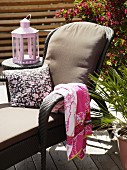 Lounger with cushion, towel and scatter cushion in front of lantern on side table