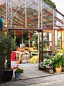 Blick in offenes, modernes Gewächshaus mit gemütlichen Gartenmöbeln