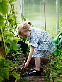 Ein Mädchen gießt die Pflanzen im Gewächshaus