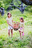 Zwei Mädchen mit Korb im Garten