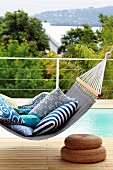 Patterned cushions on comfortable, blue canvas hammock above two woven seagrass pouffes