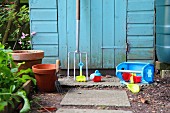 Gartengeräte und Spielzeug vor blauer Holzwand