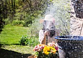 Frau bei Wasserspielen in sonnigem Garten