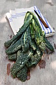Washed cavolo nero (organic) with a linen cloth and a knife on a wooden table outdoors