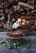 Apple cake with fresh apples in a basket on woodpile background