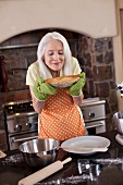 Ältere Frau in der Küche riecht an frisch gebackenem Pie