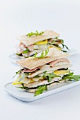 A club sandwich made with toasted crustless white bread, rocket, chicken, Parma ham, mango, parmesan and mayonnaise