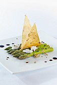 Green asparagus on wooden skewers with goat's cheese, balsamic vinegar and sheets of strudel pastry