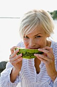A woman eating a watermelon by the sea in the archipelago of Stockholm, Sweden.