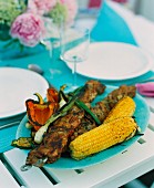 Barbecued kebabs and vegetables on a table outdoors