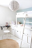 White, children's bedroom with black shelf and spherical paper lampshade with black polka dots; storage boxes integrated into bunk beds and country-house chair