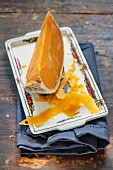 A wedge of Mimolette cheese with shavings