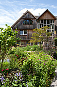 Overgrown, flowering garden in front of traditional wooden house with three-storey bay in Bergisches Land, Germany