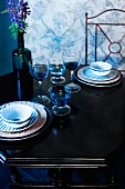 Two place settings with glasses and bottle of lupins on antique table
