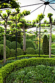 Wrought iron pavilion above concentric planting scheme of hedges and foliage plants