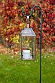 Candle lantern hanging on metal crook in garden