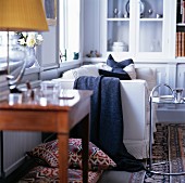 Weisses Sofa in traditionellem Wohnzimmer; im Vordergrund ein verchromter Beistelltisch