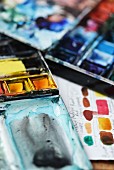 Two artist s watercolour palettes filled with paints in shades of blue and yellow