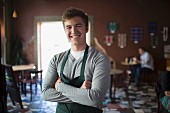 Portrait of young waiter in coffee house