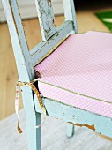 Pink seat cushion in romantic country-house style on worn kitchen chair