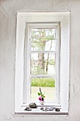 Lattice window in thick wall with collection of pebbles on windowsill